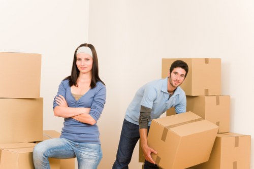 Professional movers carrying household furniture through a hallway in Erith